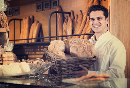 Man selling  pastry and baguettes in local bakeryの写真素材