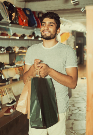 portrait of positive man with paper bags in the modern shopの写真素材