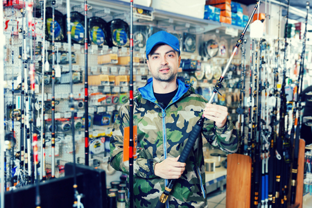 Male customer in fishing clothing choosing  fishing rod in the sports shop
の写真素材