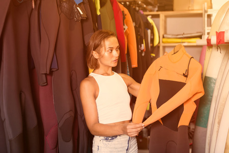 Adult american woman surfer choosing suit for surfing in the shop
の写真素材
