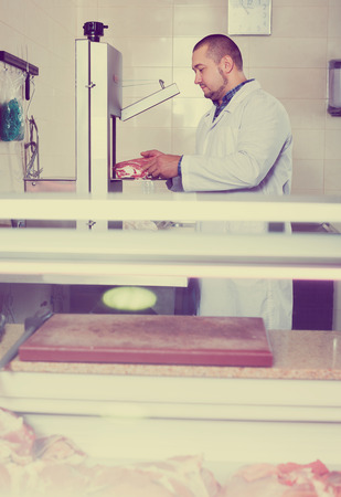 Salesman near scales and display with cooled lamb meatの写真素材
