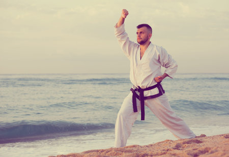 Man is exercising to doing the Kokutsu-dachi stance on the beach near the sea.の写真素材