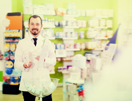 Positive male pharmacist suggesting useful drug in pharmacyの写真素材
