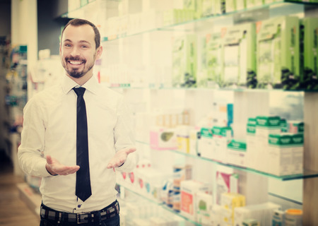 Young male customer searching for reliable drug in pharmacyの写真素材
