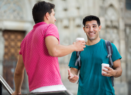 Men friends are talking and drinking coffee in time walking at city の写真素材