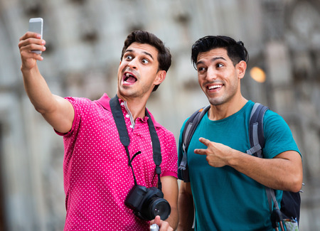 Two cheerful  smiling friends are walking with baggage and making selfie in Barcelona.の写真素材