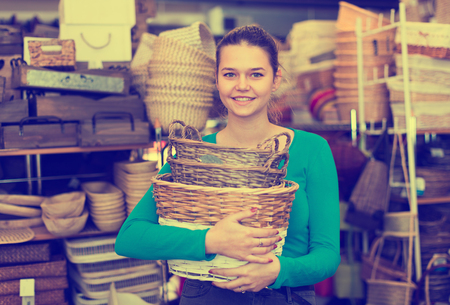 Female teen standing with wicker basket in decoration and furniture store の写真素材