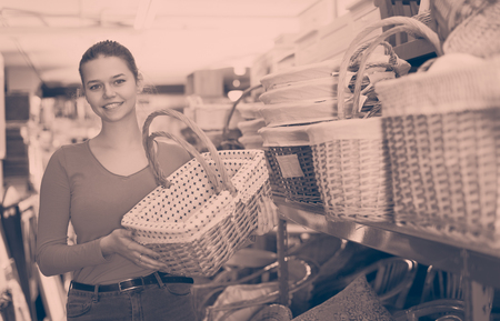 beauty young girl customer standing with wicker basket in shop for decorの写真素材