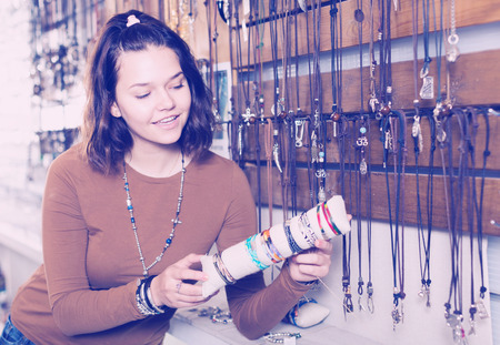 Cheerful young woman selling different pendants and bracelets in the marketの写真素材