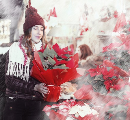 Portrait of girl customer choosing floral decorations for Christmas outdoorの写真素材