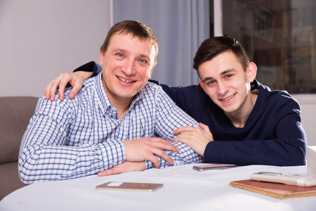 Portrait of adult male with his son who are resting together and posing at the home.