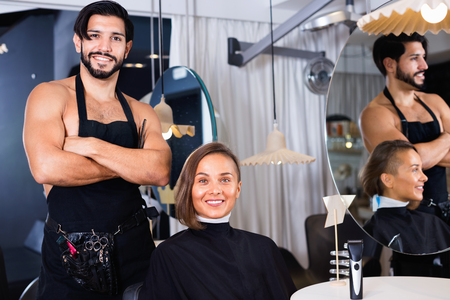 Happy  male professional with female talking about hairstyleの写真素材