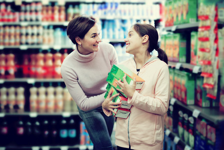 Beautiful young woman customer with girl looking for refreshing beverages in supermarketの写真素材