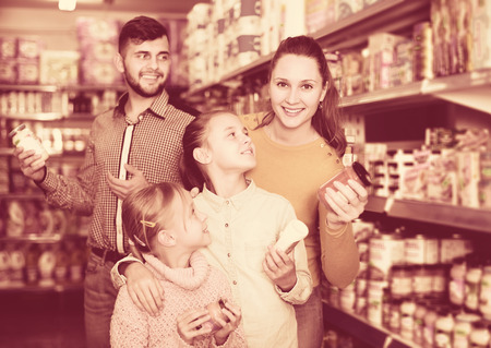 Young glad family of four shopping together in grocery storeの写真素材