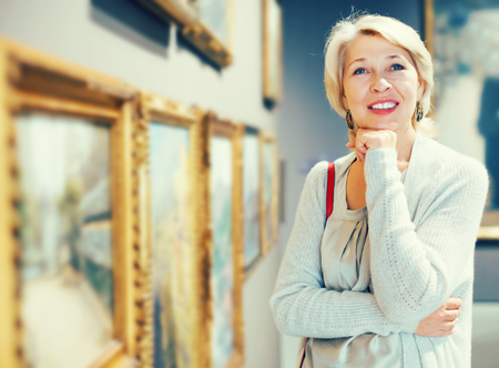 Positive mature female near picture collection in the museumの写真素材