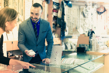 Cheerful man offering to buy stylish bracelets in the shop of jewelryの写真素材
