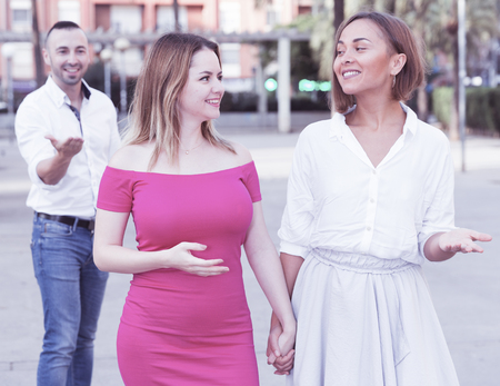 Young women are walking and stranger man is want acquaintance with them on the street.の写真素材