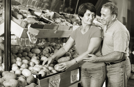 Smiling cheerful  couple is choosing potato in the supermarket.の写真素材