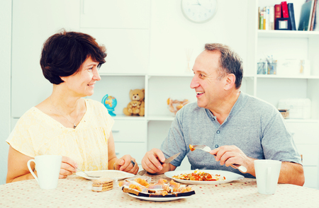 cheerful senior couple having lunch together at home の写真素材