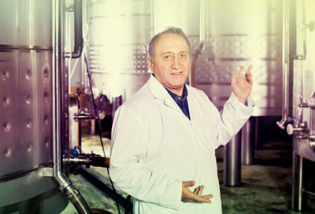 Elderly man in uniform works with equipment to winery