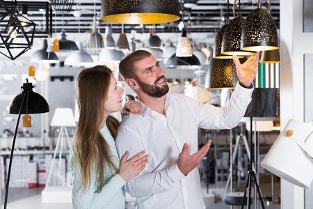 Happy couple choosing pendent lamp in  furniture  showroomの写真素材