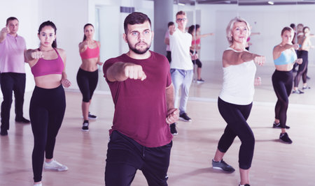 active men women of different ages posing in fitness studio