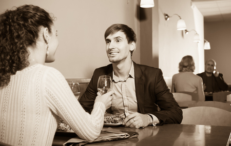 Young man and girlfriend chatting as having date in restaurantの写真素材