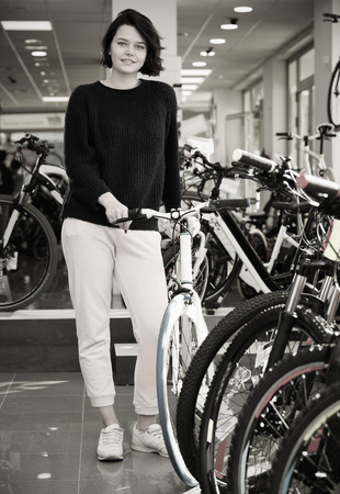 Young girl showing with sport bike in bicycle storeの写真素材