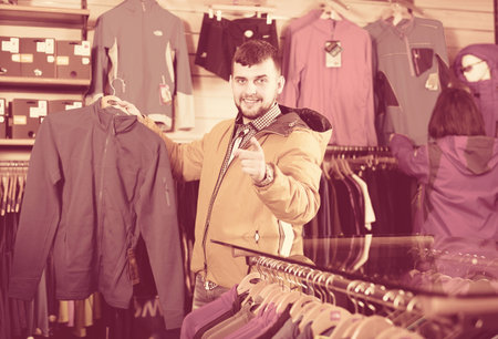Young couple deciding on track jacket in sports clothes store