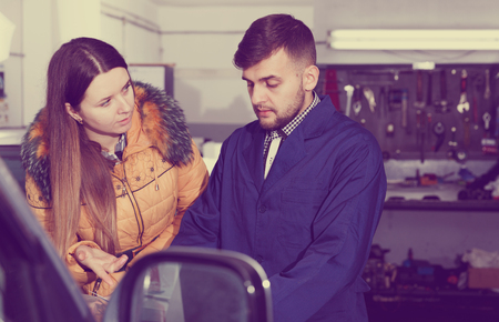 Female is dissatisfied of tire winter replacement of her car in workshop.の写真素材