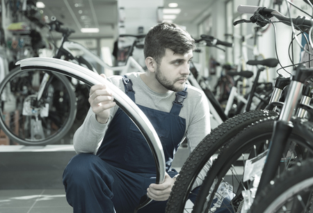 Cheerful professional man holding cycle frame in bicycle shopの写真素材