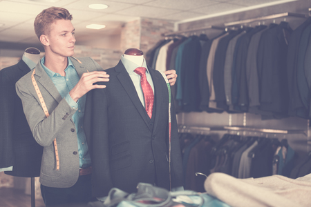 Seller in business clothes measuring jacket in the dress shopの写真素材