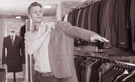 Portrait of man costumer trying business style jacket in the shopの写真素材