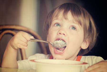Child himself eats cereal with a spoonの写真素材