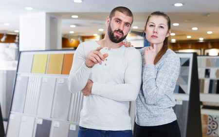 Smiling family couple standing and point with finger to tile  in  shopの写真素材