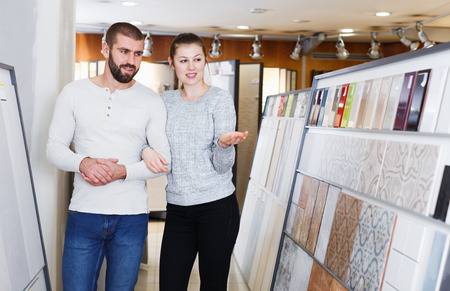 Smiling family couple choosing ceramic tile  in domestic shopの写真素材