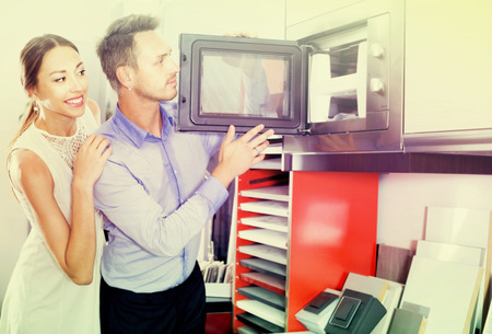 Smiling family couple choosing new microwave in furniture showroomの写真素材