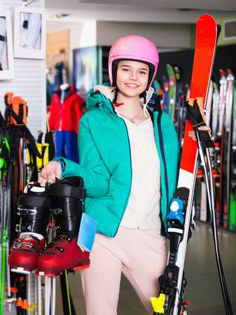 Smiling cheerful  glad young woman standing with purchased ski equipment in shopの写真素材