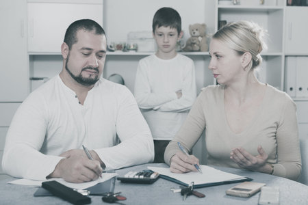 Parents calculating family budget and utility at home while son standing behind