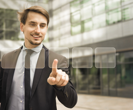 Man in business suit pressing icons on virtual digital touchscreenの写真素材