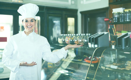 Young female assistant demonstrating assortment of confectionery