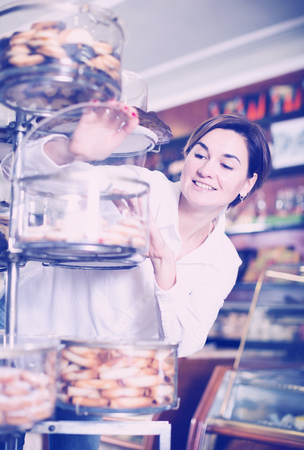 Young female customer examining desserts in confectioneryの写真素材