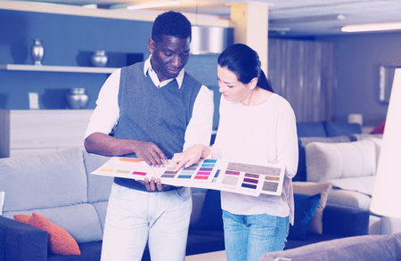 African man with his girlfriend are choosing modern materials for furniture for their home in the shopの写真素材