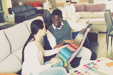 Positive african man with his wife are choosing modern materials for furniture for their home in the storeの写真素材