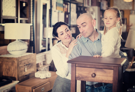 Family couple with small daughter are choosing furniture  in furniture  showroomの写真素材