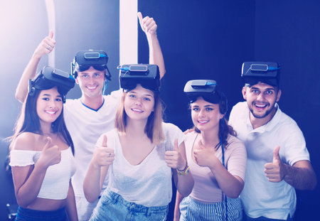 Smiling people expressing satisfaction with vr attraction showing thumbs up