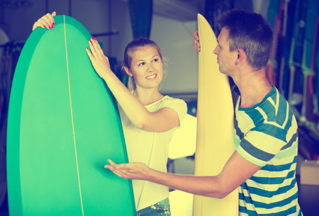 Man with woman choosing surfboard in shop in time summer holidaysの写真素材
