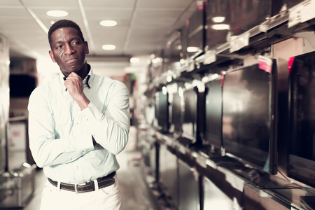 Glad man chooses TV set in store of household appliancesの写真素材