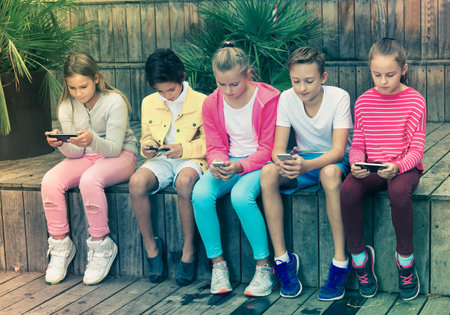 glad kidsare chatting on their smartphone on walking.