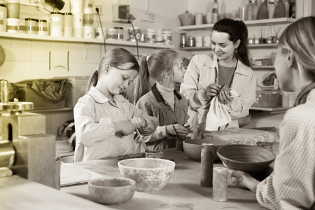 happy russian female teacher helping teenagers at making pottery during arts and crafts classの写真素材